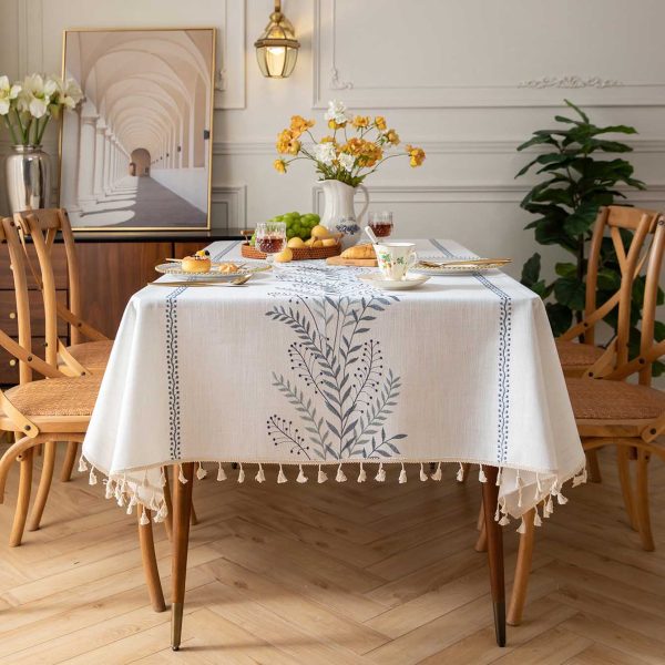 Outdoor patio table covered with oval embroidered tablecloth showcasing elegant tassels and tranquil design