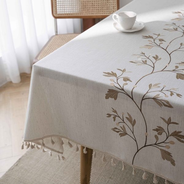 Cozy fall dining scene with rustic embroidered tablecloth and pumpkins