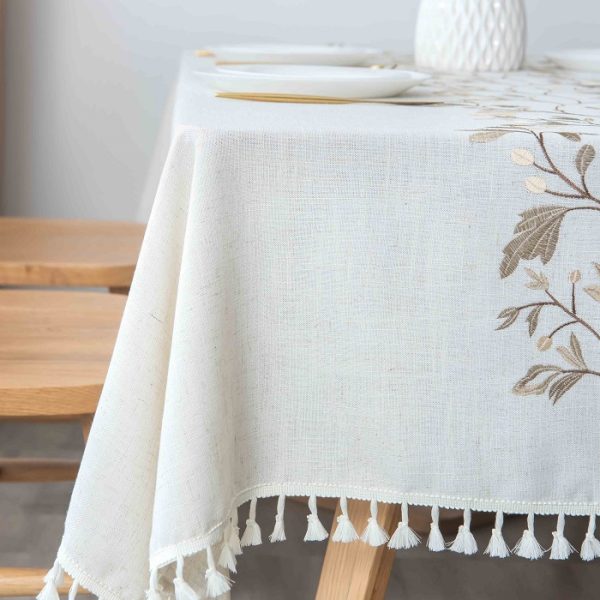 Embroidered faux linen tablecloth with beige leaf vine pattern on wood dining table