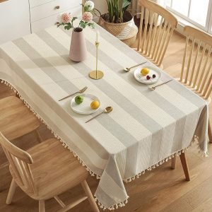 Striped cotton linen tablecloth with tassels on a wooden dining table