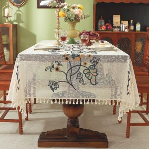 Embroidered floral vintage table linens with tassel edges on wooden dining table