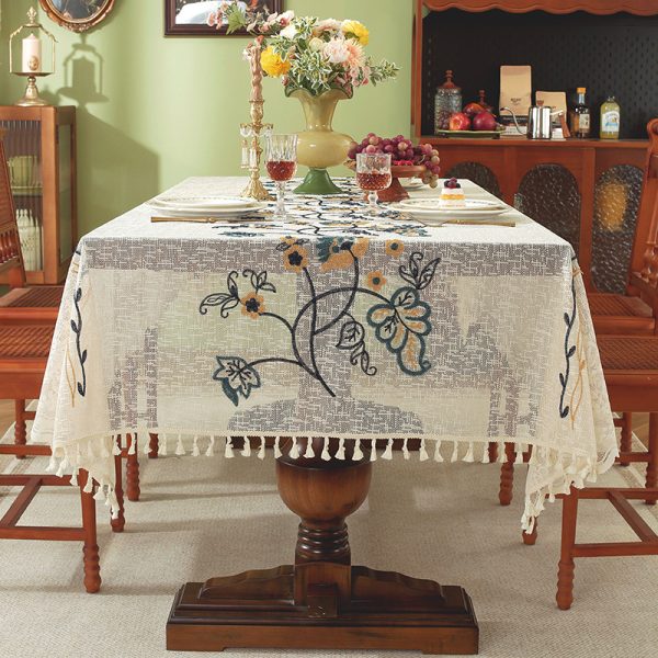 Embroidered floral vintage table linens with tassel edges on wooden dining table