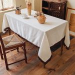 Beige cotton linen tablecloth with tassels on wooden table