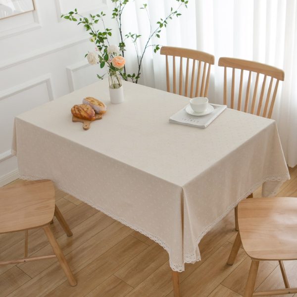 Vintage cotton linen tablecloth with daisy floral pattern and lace trim on wooden dining table