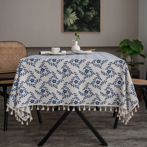 Blue floral cloth tablecloth folded neatly with tassel fringe visible