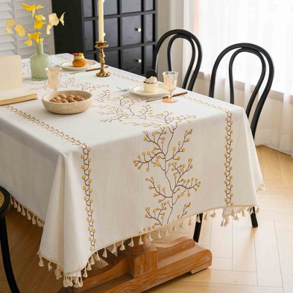 Embroidered beige faux linen tablecloth with brown berry design on dining table