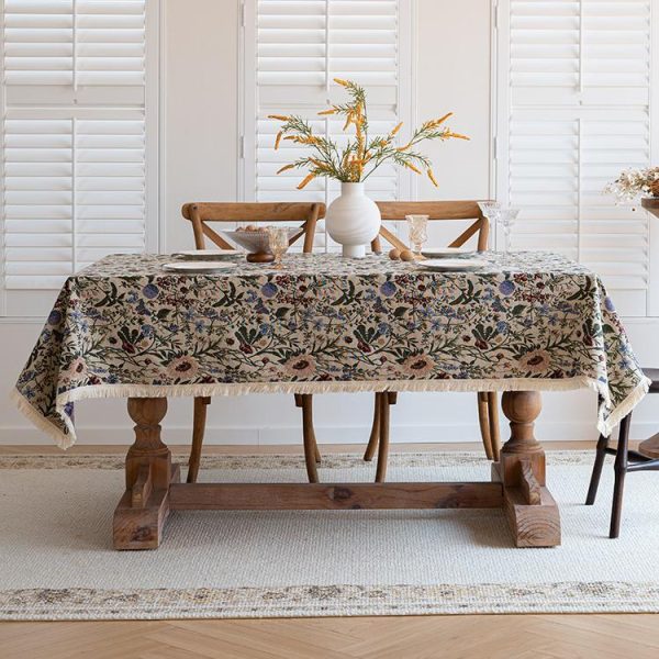 Vintage cotton linen tablecloth with floral print and tassel trim on rustic wooden dining table